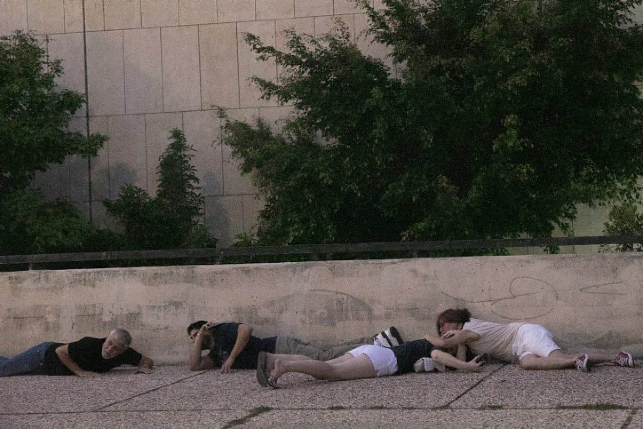 Israelis take cover as a rocket warning siren sounds in "Hostage Square" outside the Tel Aviv Museum of Art, Oct. 28, 2023. Photo by Miriam Alster/Flash90.
