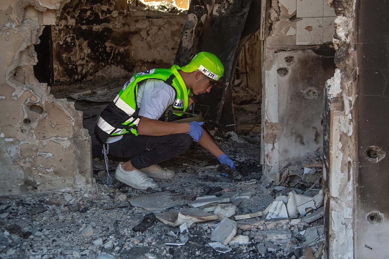 Members of ZAKA walk through the destruction caused by Hamas terrorists in Kfar Aza near the border with Gaza, as they collect the dead bodies of Israelis on Oct. 15, 2023. Photo by Edi Israel/Flash90.