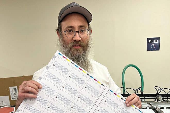 Rabbi Menachem Traxler of Colel Chabad with debit cards printed in Kibbutz Be'eri for displaced Israelis to use for basic needs following the terrorist attacks of Oct. 7, 2023. Credit: Courtesy,