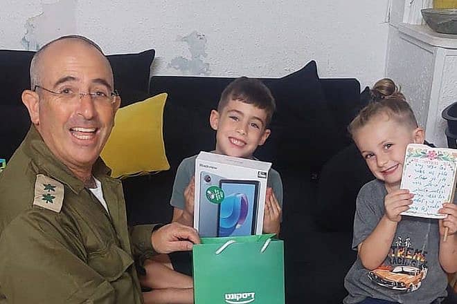 Lt. Col. Eliya Eshel delivers a tablet computer to a child with special needs. Credit: Special in Uniform.
