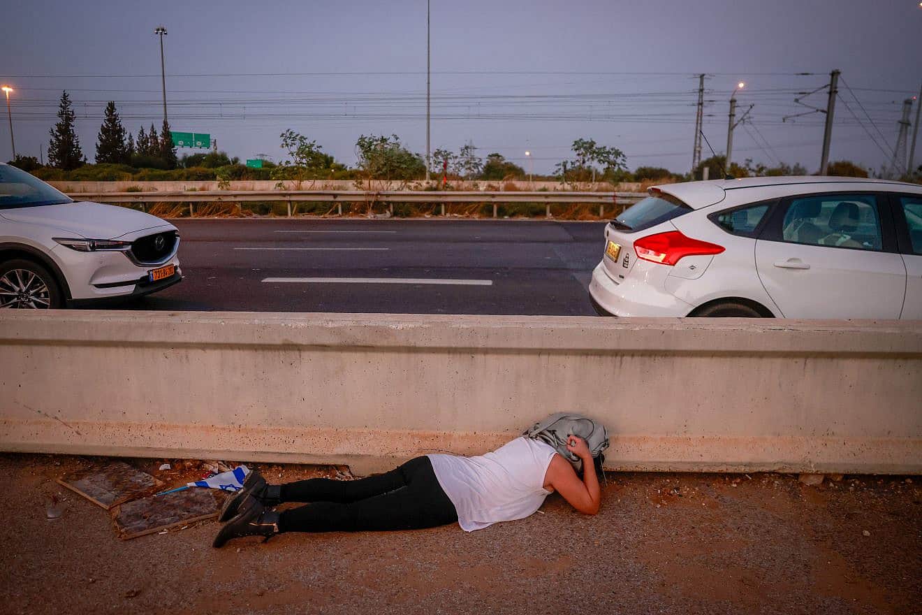 Israelis take cover on a road in central Israel as an air-raid siren warns for incoming rockets, Nov. 2, 2023. Photo by Chaim Goldberg/Flash90.