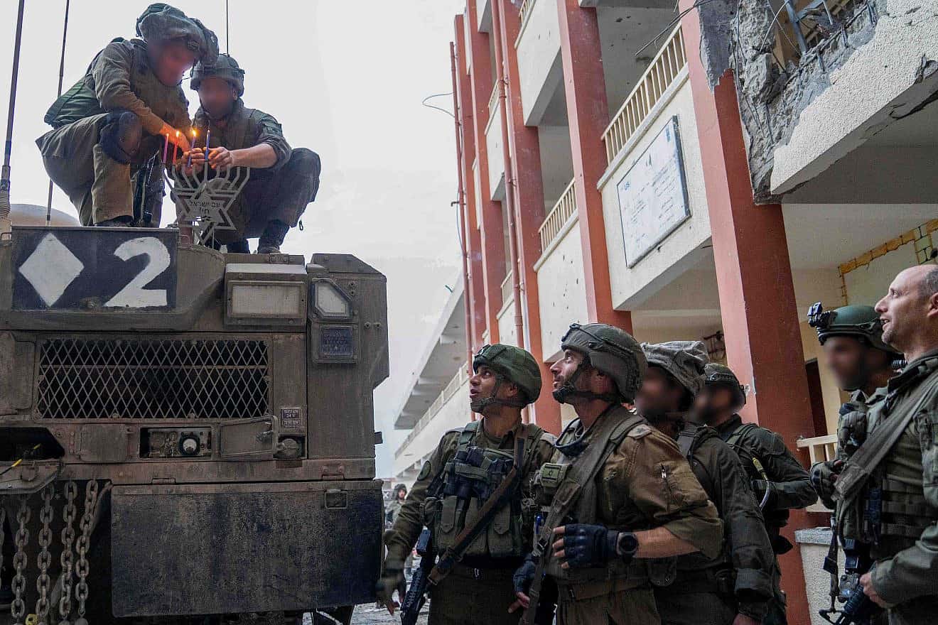 Israeli soldiers in the Gaza Strip light a menorah for the third night of Chanukah, Dec. 9, 2023. Credit: IDF.
