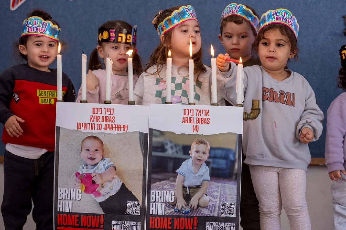 Photographs of Hamas captives Kfir and Ariel Bibas on a menorah being lit by children at a kindergarten in Moshav Yashresh on Dec. 12, 2023. Photo by Yossi Aloni/Flash90.