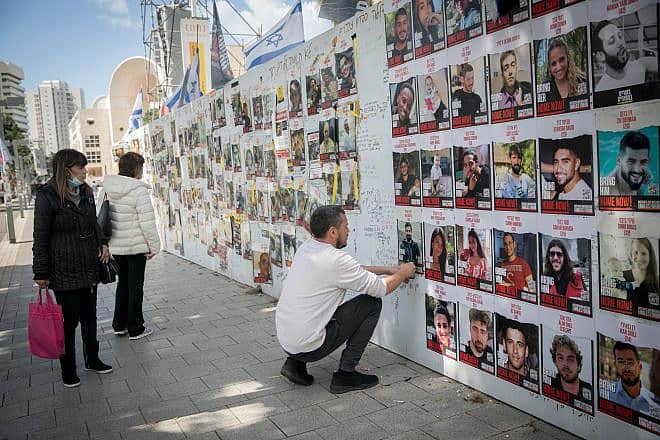 A man posts photographs of the Israelis still being held captive in the Gaza Strip by Hamas terrorists at "Hostages Square" in Tel Aviv on March 4, 2024. Photo by Miriam Alster/Flash90.