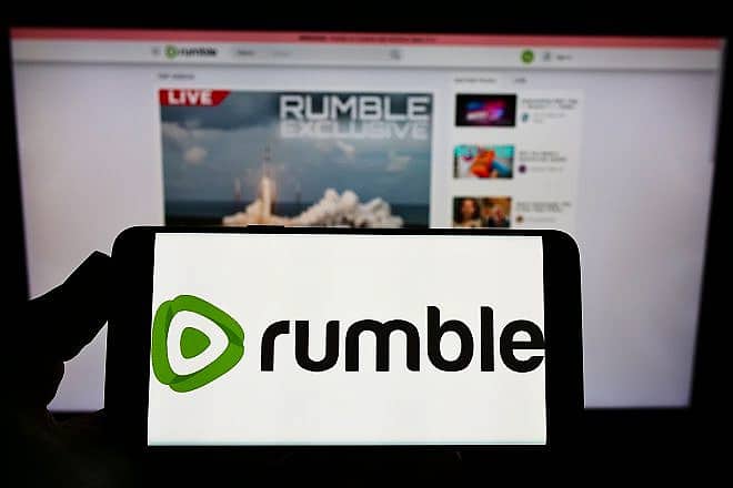 A smartphone with the logo of Canadian video-platform company Rumble Inc. on screen in front of its website. Credit: T. Schneider/Shutterstock.