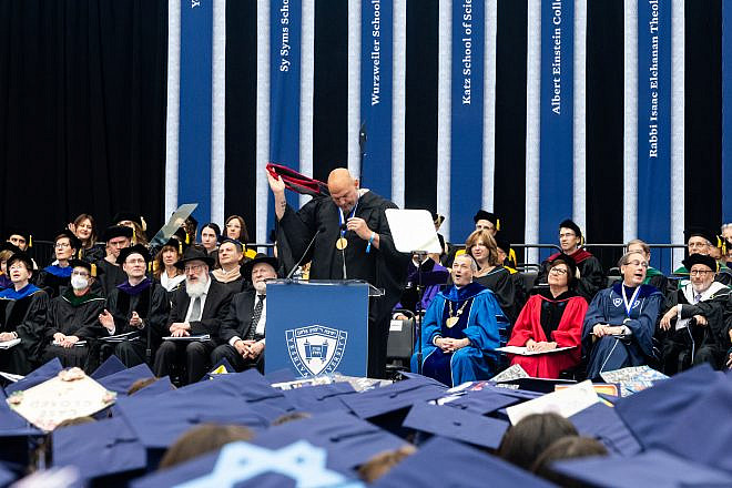 Sen. John Fetterman (D-Pa.) removes the hood from his Harvard robe at Yeshiva University's commencement ceremony in New York on May 29, 2024. Credit: Yeshiva University.