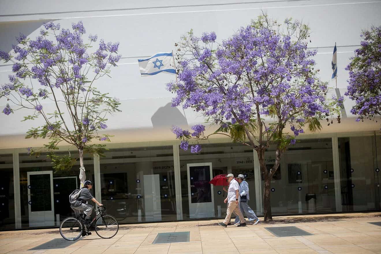 Biking and walking by jacaranda trees  on Habima Square in Tel Aviv on May 16, 2024.  Photo by Miriam Alster/Flash90.