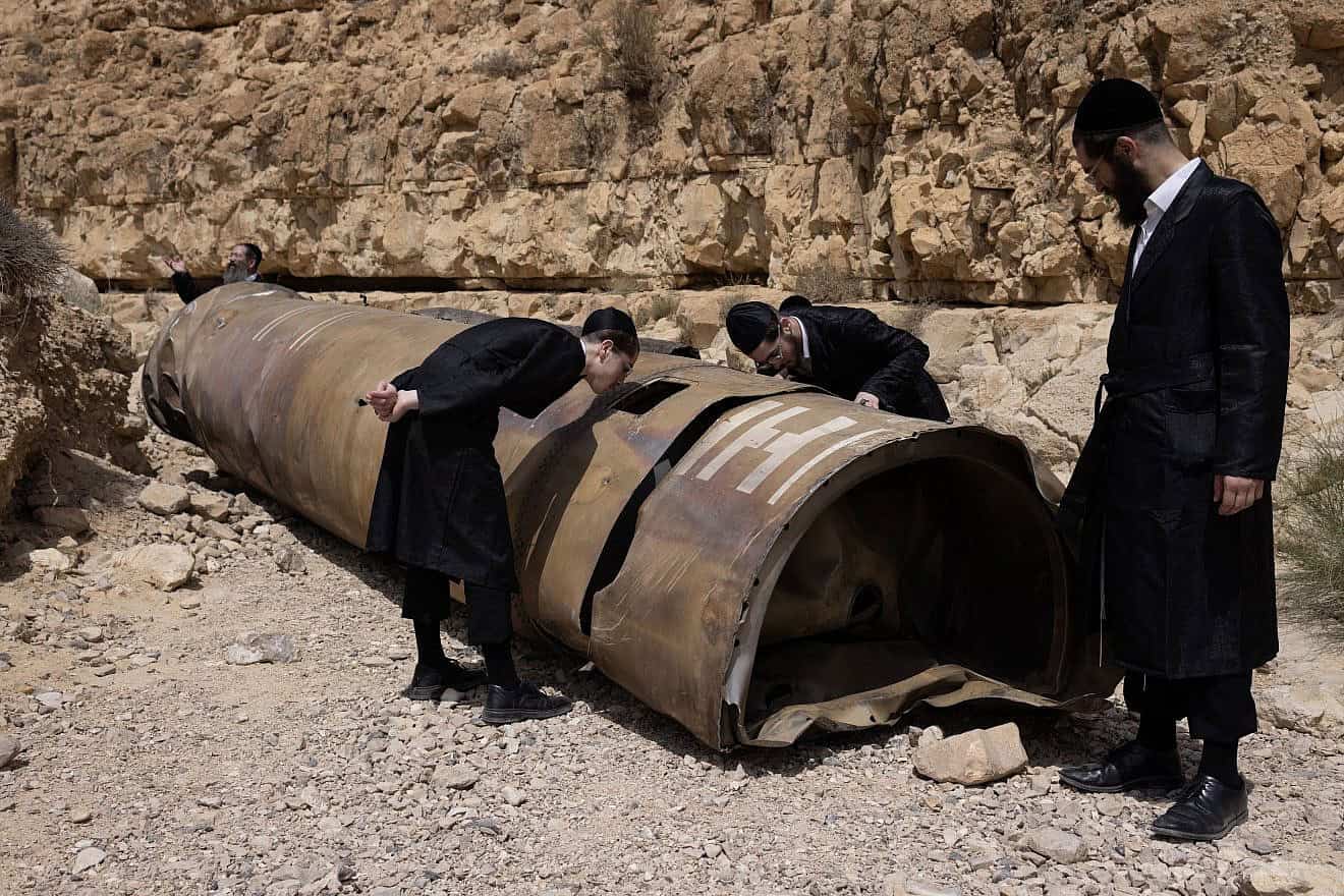 Haredi Jews examining the remains of a rocket fired from Iran, near the southern Israeli city of Arad, April 28, 2024. Photo by Oren Ziv/Flash90.