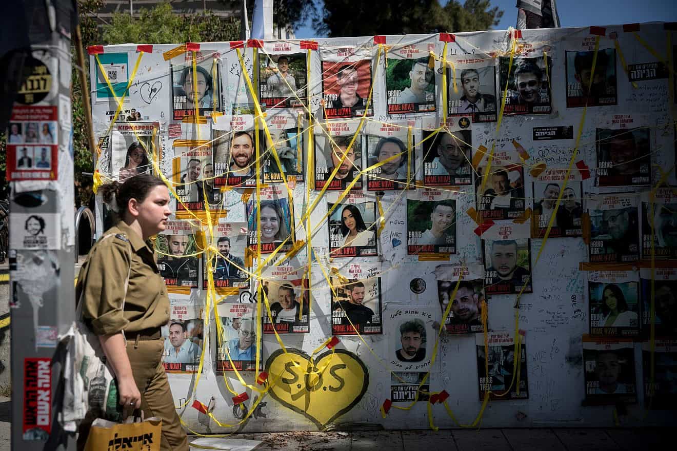 A woman walks past pictures  at "Hostage Square" in Tel Aviv of Israelis held hostage by Hamas terrorists in Gaza, June 16, 2024. Photo by Miriam Alster/Flash90.