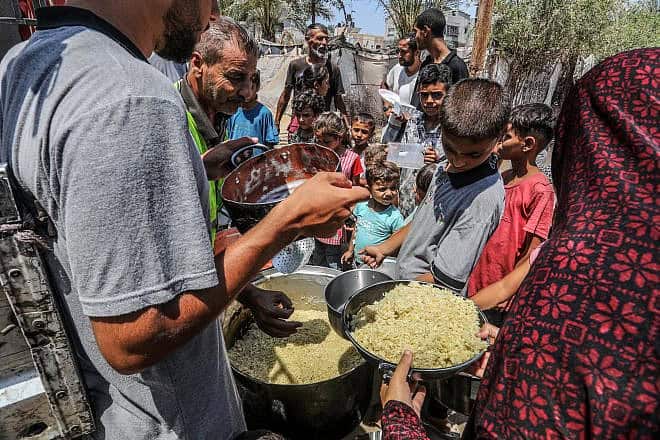 Palestinians receive a hot meal prepared by volunteers in Deir al-Balah, in the central Gaza Strip, on June 13, 2024. Photo by Abed Rahim Khatib/Flash90.