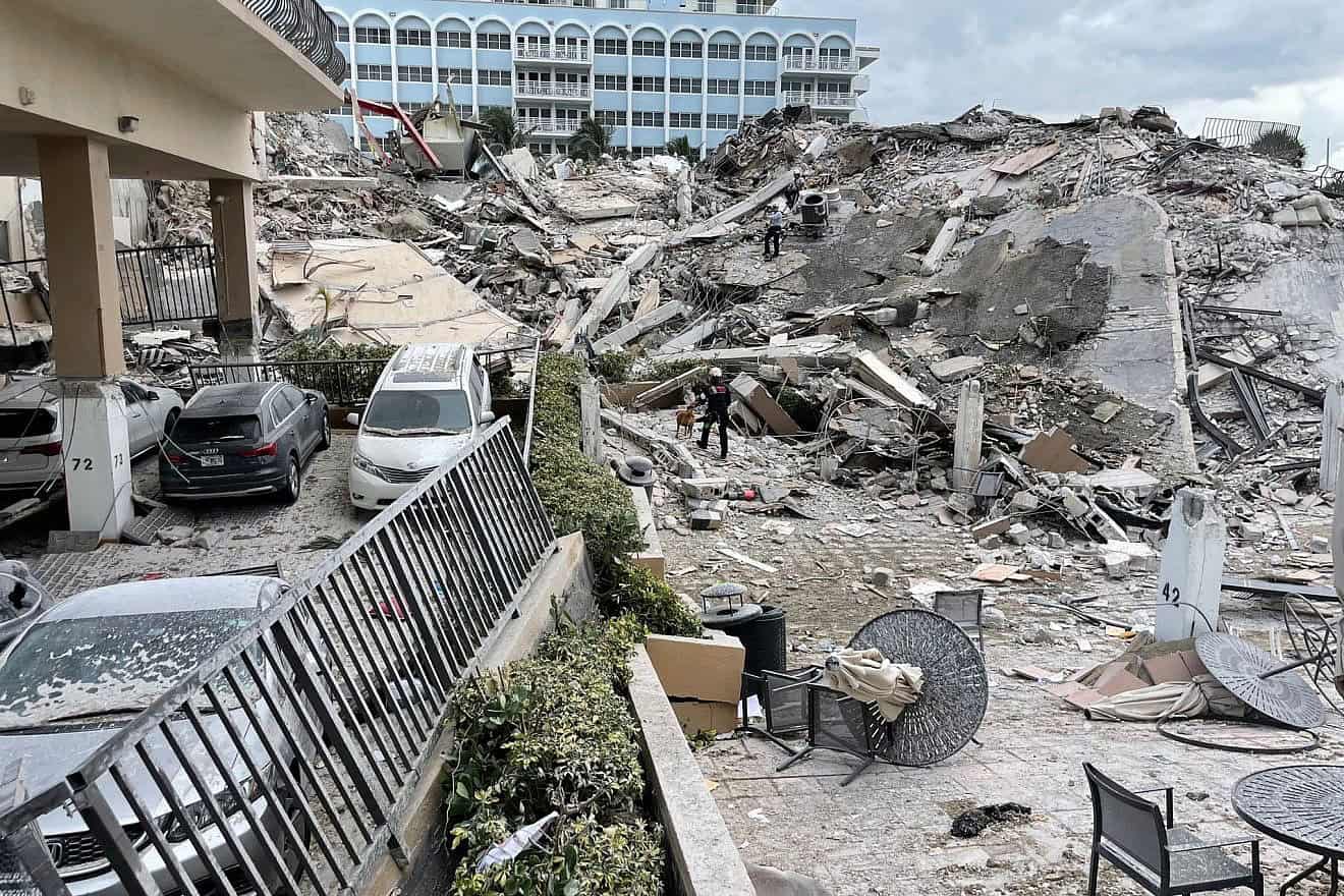 A ground view of the partially collapsed Champlain Towers South condo building, where rescuers and a rescue dog work within the rubble area to search for survivors, June 24, 2021. Credit: Miami-Dade Fire Rescue Department via Wikimedia Commons.