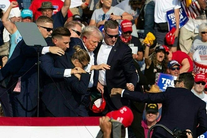 Republican presidential candidate Donald Trump is seen with blood on his face surrounded by secret service agents following an assassination attempt in Butler, Pennsylvania on July 13, 2024. Credit: Rebecca Droke / AFP via Getty Images.