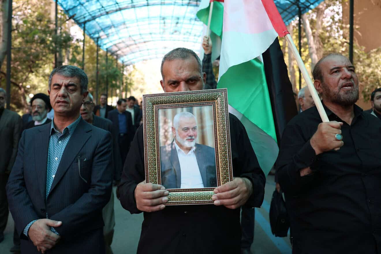 Men hold up a PLO flag and a portrait of slain Hamas chief Ismail Haniyeh during a rally at Tehran University, as Iran declares three days of mourning, on July 31, 2024. Photo by AFP via Getty Images.