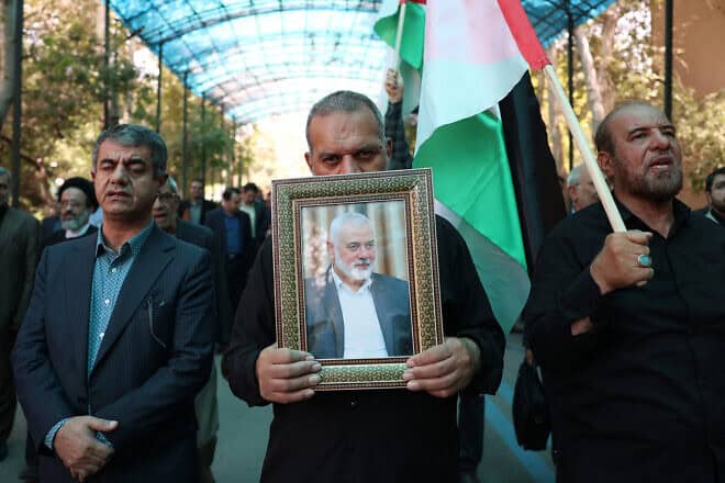 Men hold up a PLO flag and a portrait of slain Hamas chief Ismail Haniyeh during a rally at Tehran University, as Iran declares three days of mourning, on July 31, 2024. Photo by AFP via Getty Images.