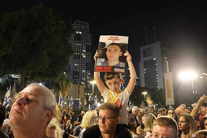 Roi Angrest holds a poster depicting his brother Matan at a protest. Credit: The Hostages and Missing Families Forum.