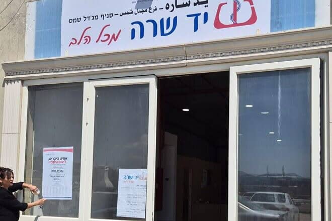 Yad Sarah volunteer taping a condolence notice on the door of the Majdal Shams branch. Credit: Courtesy.