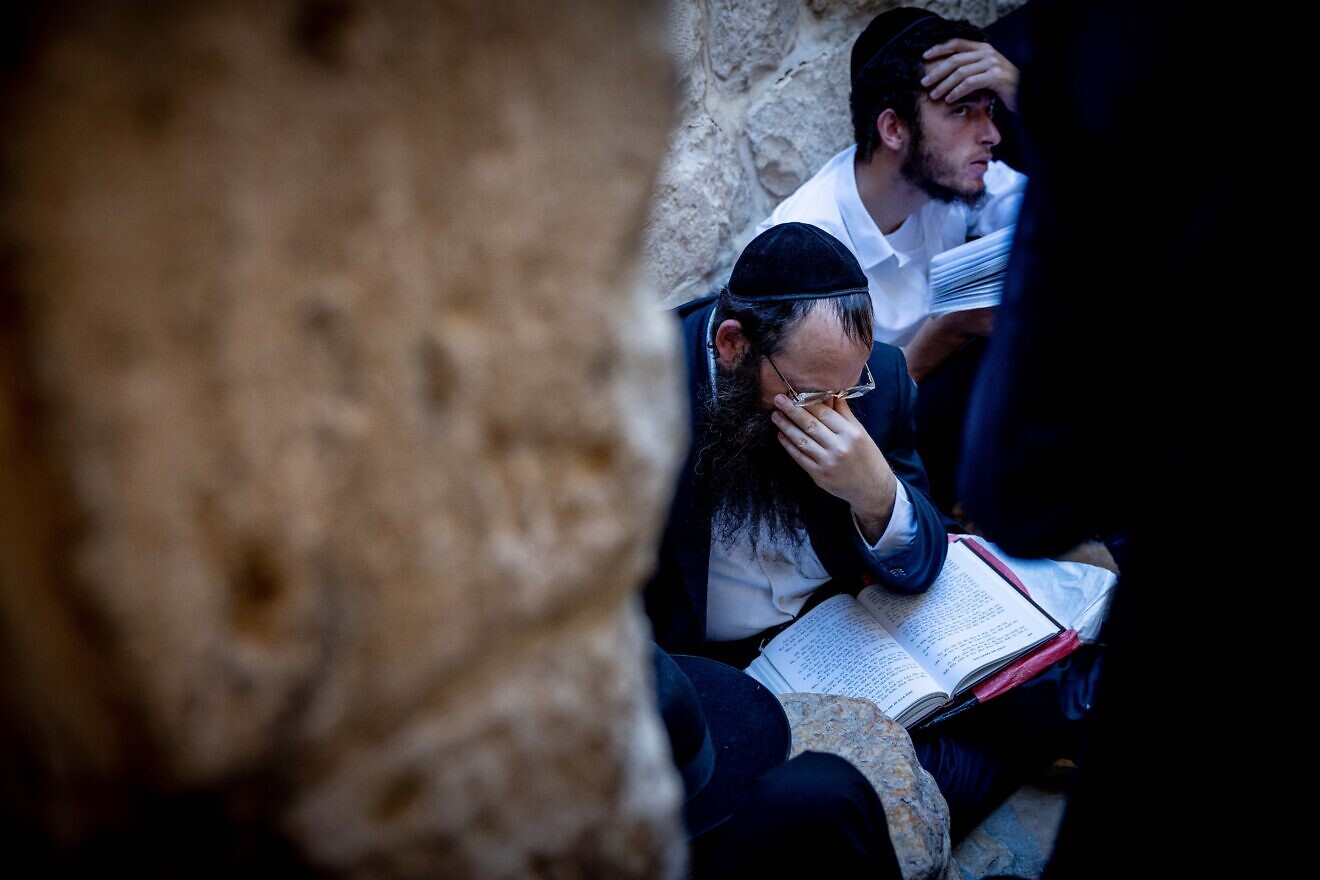 Worshippers pray sitting on the ground in mourning at the Western Wall in Jerusalem's Old City on Tisha B'Av, on July 27, 2023. Photo by Chaim Goldberg/Flash90.