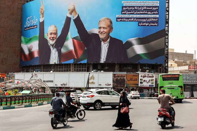Iranians pass by a billboard of the late Hamas terror leader Ismail Haniyeh (left) and President Masoud Pezeshkian at Valise Square in Tehran, Aug. 1, 2024. Photo by AFP via Getty Images.