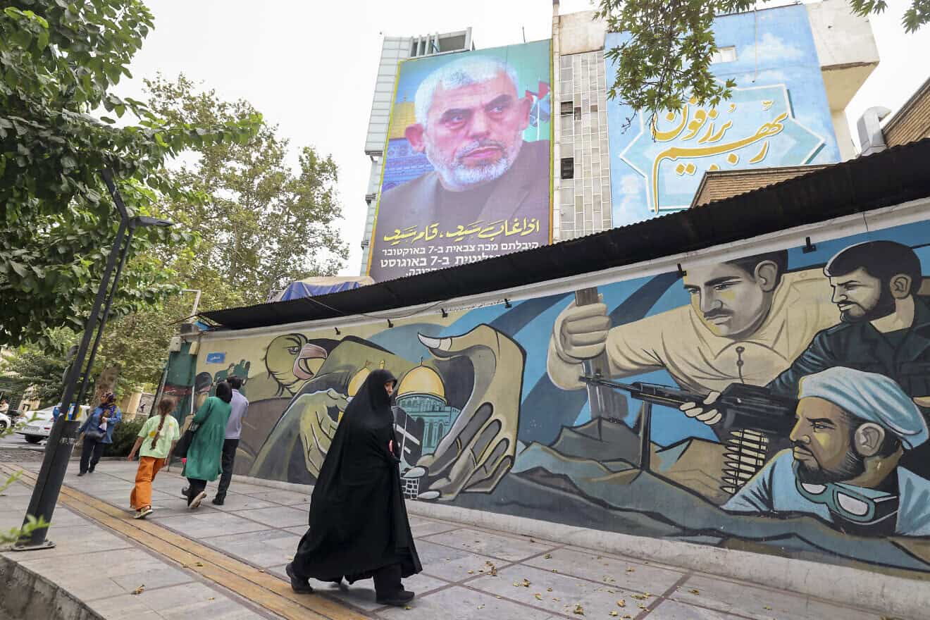 People walk past a billboard showing a portrait of newly appointed Hamas leader Yahya Sinwar (top) next to Palestine Square in the Tehran on Aug. 12, 2024. Photo by Atta Kenare/AFP via Getty Images.