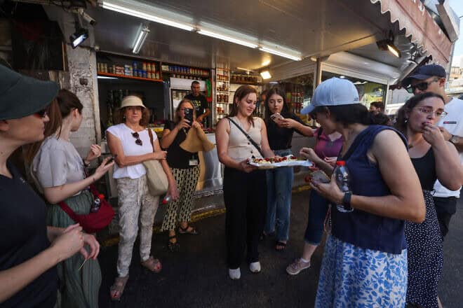 People try bites from a tasting platter offered by a shop at a market in Haifa on Aug. 5, 2024. Photo by Menahem Kahana/AFP via Getty Images.