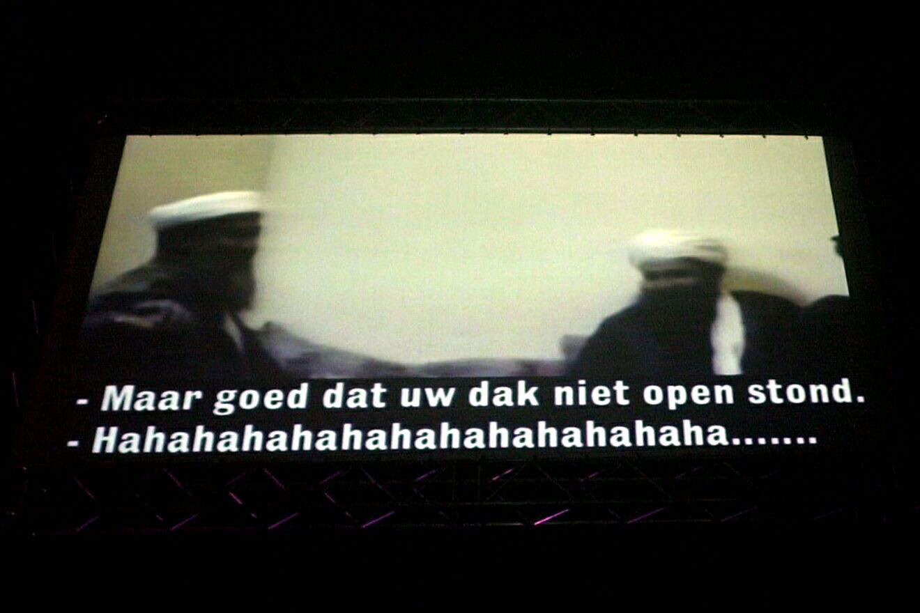 A screen displays a video of Osama bin Laden (left) after he was appointed “Man of the Year” by “Humo” magazine during its “Pop Poll” election in Brussels, March 12, 2002. A humoristic “translation” reads: “What a luck that your roof is closed ... Hahahahahaha.” Photo by Oliver Matthys/Belga/AFP via Getty Images.
