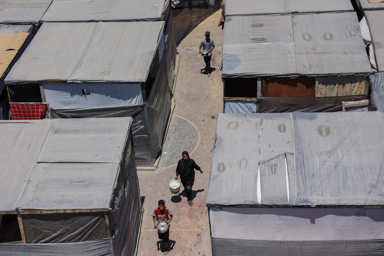 Palestinians carry food and water at a U.N. Relief and Works Agency for Palestine Refugees (UNRWA) school in the Jabalia refugee camp in the northern Gaza Strip on July 23, 2024. Photo by Omar Al-Qattaa/AFP via Getty Images.