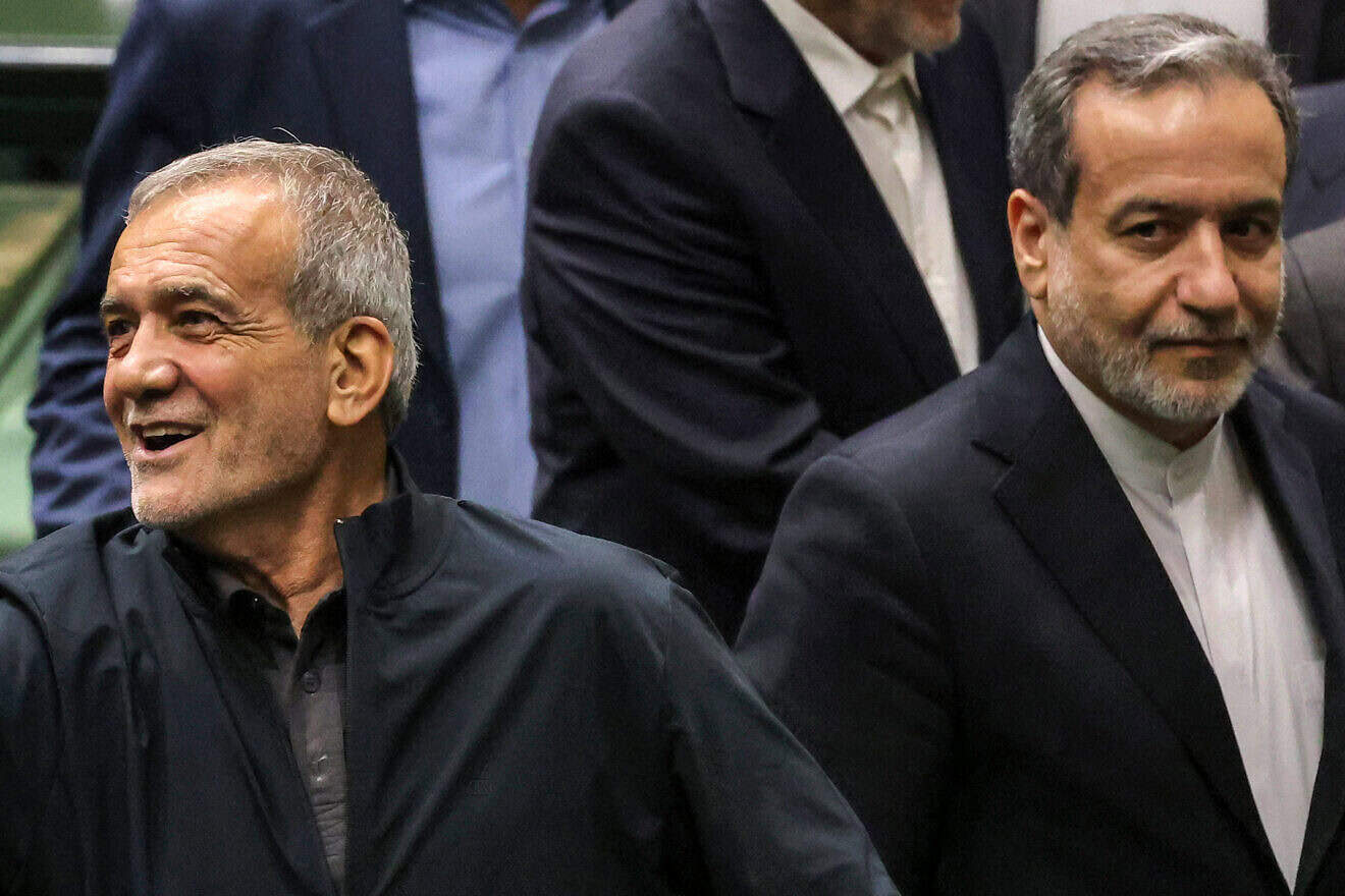 Iran's President Masoud Pezeshkian (L) reacts next to his nominee for the foreign ministry cabinet position Abbas Araghchi (R) as the former greets parliament members after giving an address during a session to approve his new cabinet appointments in Tehran on Aug. 21, 2024. Photo by Atta Kenare/AFP via Getty Images.