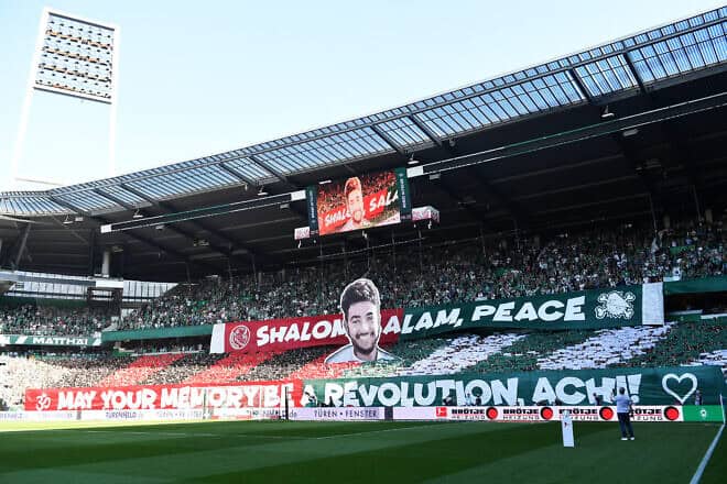 Fans display banners reading, "Shalom, Salam, Peace, May Your Memory be a Revolution, Achi" during the Bundesliga match between SV Werder Bremen and FC Bayern München at Weserstadion in Bremen on Sept. 21, 2024. Photo by Stuart Franklin/Getty Images.