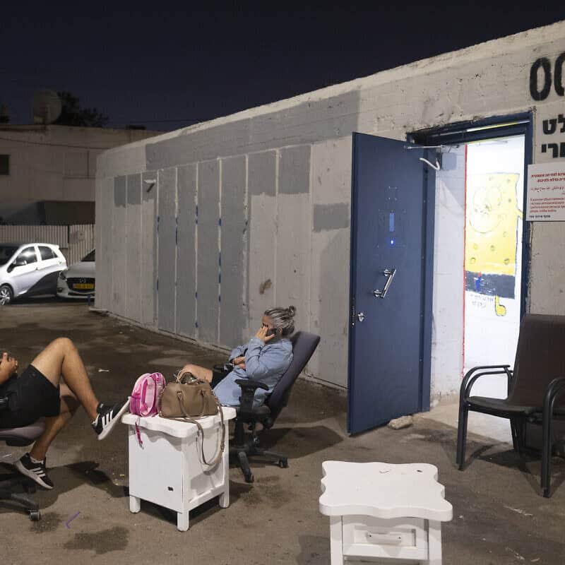 Moshe Aladi and a relative sit outside a municipal shelter in Haifa on Sept. 24, 2024. Photo by Canaan Lidor.