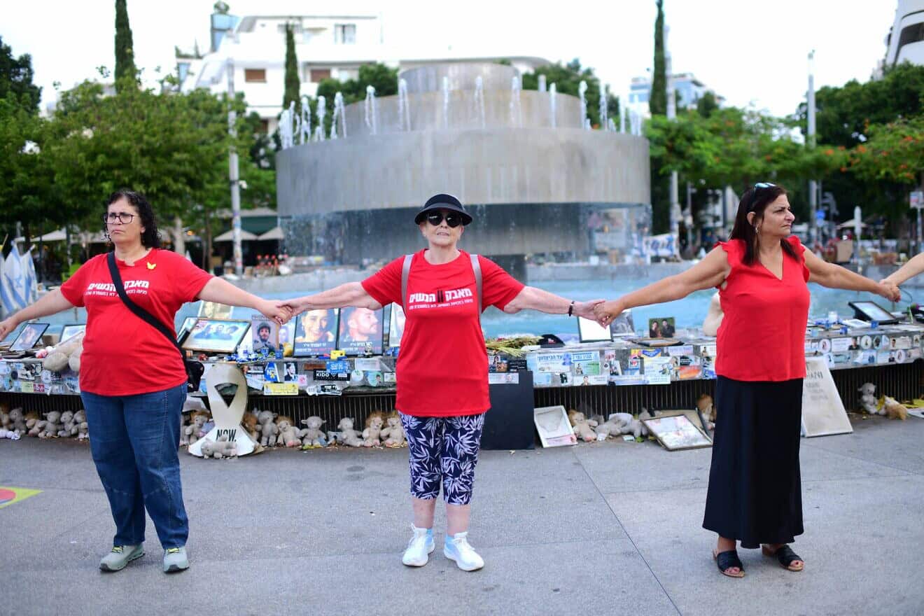 Israelis hold hands at Dizengoff Square in Tel Aviv, next to photographs of Israelis killed in the Oct. 7 massacre, on the one-year anniversary of the Hamas attack. Oct/ 7, 2024. Photo by Tomer Neubergi/Flash90.