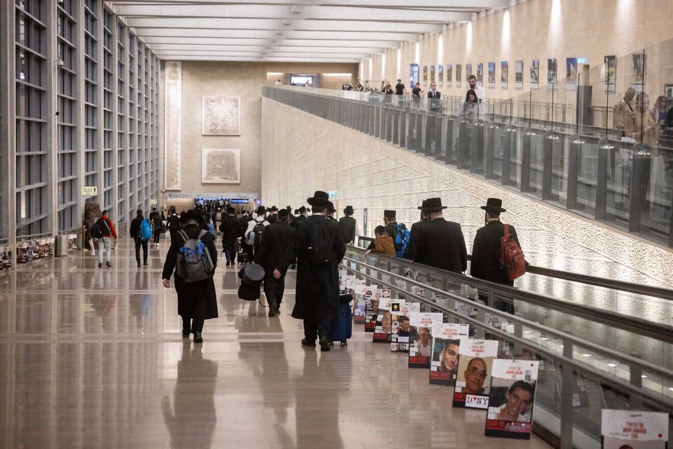 Travelers walk next to pictures of Israelis held hostage by Hamas in the Gaza Strip at Ben-Gurion International Airport, Oct. 8, 2024. Photo by Chaim Goldberg/Flash90.