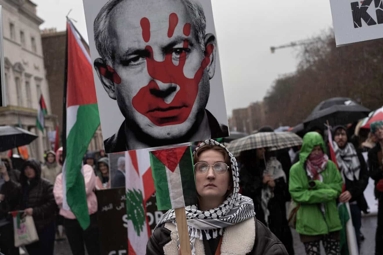 A female protester raises a placard with a depiction of a red hand on the face of Israeli Prime Minister Benjamin Netanyahu during a protest held by the Ireland-Palestine Solidarity Campaign in Dublin on Feb. 17, 2024. Photo by Natalia Campos/Getty Images.