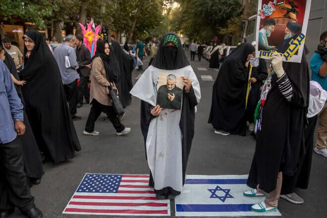 Iranians stand over imitation U.S. and Israeli flags during an anti-Israel rally in Tehran's Palestine Square on Oct. 8, 2024. Photo by Majid Saeedi/Getty Images.