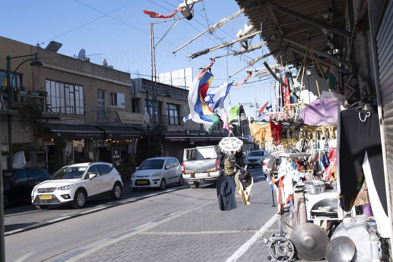 Israeli and Druze flags fly on a store front on the deserted main shopping street of Daliyat al-Karmel, near Haifa, on Oct. 21, 2024. Photo by Canaan Lidor.