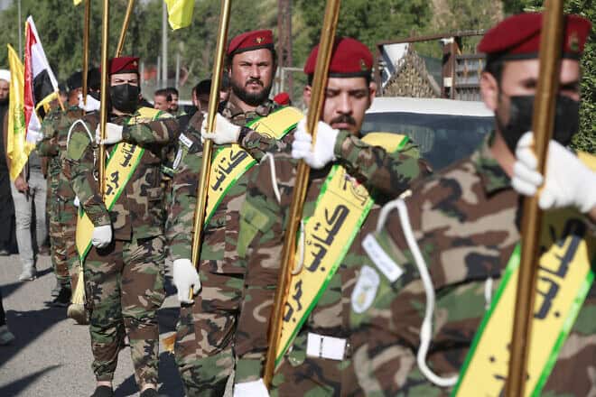 Flags of Iraq and paramilitary groups, including al-Nujaba and Kataib Hezbollah, are displayed during a funeral in Baghdad for five militants killed a day earlier in a U.S. strike in northern Iraq, on Dec. 4, 2023. Photo by Ahmad al-Rubaye/ AFP via Getty Images.