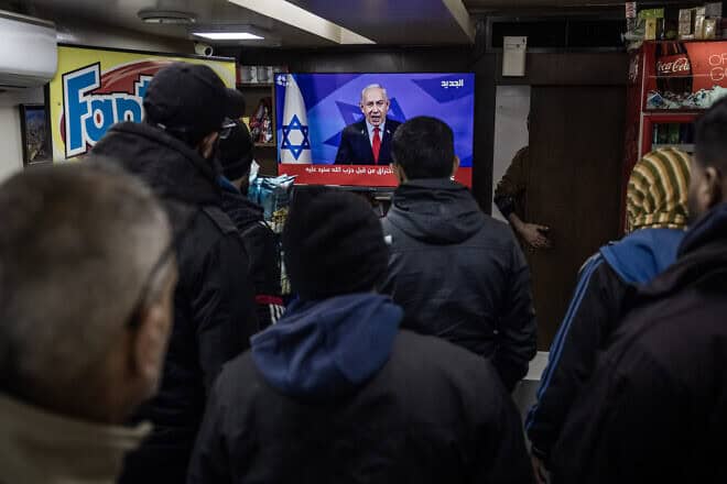 People in Lebanon watch Israeli Prime Minister Benjamin Netanyahu announce his Cabinet's approval of a ceasefire, near Martyrs Square in Beirut, Nov. 26, 2024. Photo by Ed Ram/Getty Images.