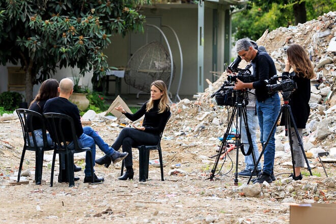 "Channel 12" journalist Adva Dadon backdropped by destruction from the massacre on Oct. 7, 2023, at Kibbutz Be'eri, Jan. 3, 2024. Photo by Moshe Shai/Flash90.