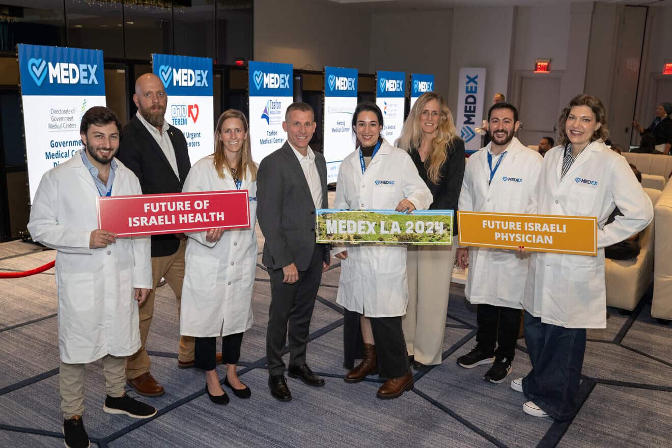 Holding signs are (from left) medical professionals Ronen Fuxman, Zev Gershinsky and Efrat Aflalo at the MedEx LA fair on Dec. 8, 2024. Photo by Shahar Azran.