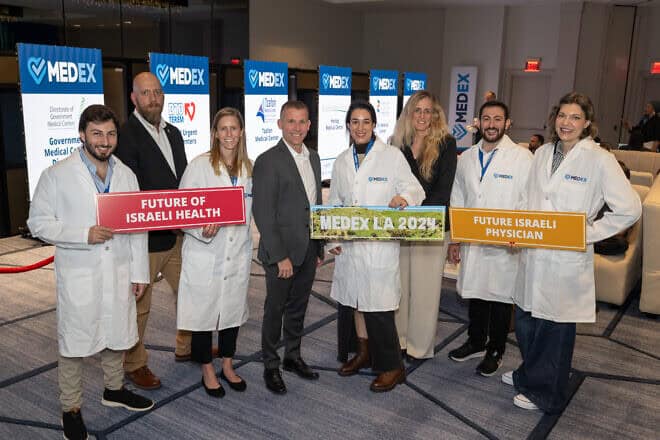Holding signs are (from left) medical professionals Ronen Fuxman, Zev Gershinsky and Efrat Aflalo at the MedEx LA fair on Dec. 8, 2024. Photo by Shahar Azran.