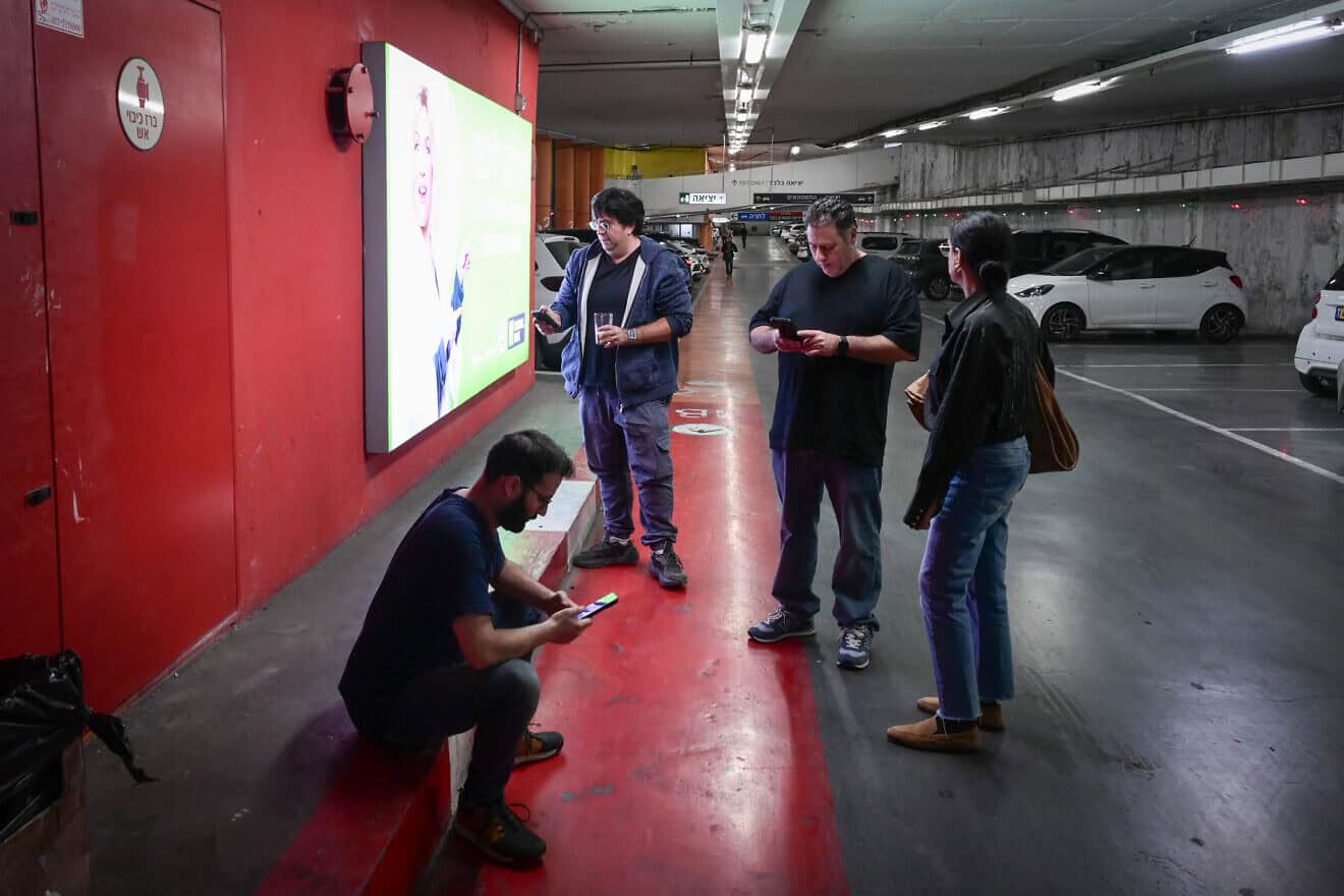 Israelis take cover in a parking garage as a missile alert is activated in Tel Aviv, Dec. 16, 2024. Photo by Avshalom Sassonif/Flash90.