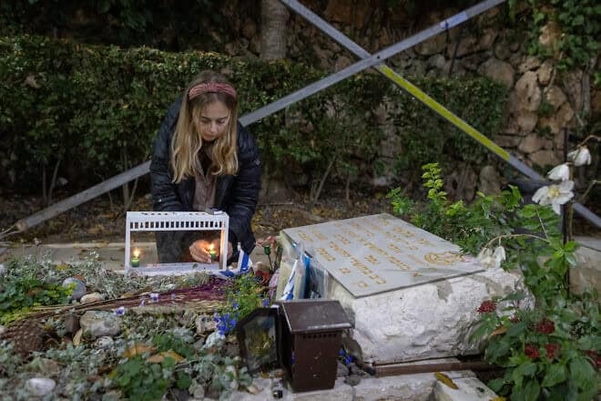 Senai Guedalia, the widow of Yosef Guedalia, a soldier in the Israel Defense Forces killed in Kibbutz Kfar Aza on Oct. 7, 2023, lights the first Chanukah candle on his grave at Mount Herzl Military Cemetery in Jerusalem on Dec. 25, 2024. Photo by Chaim Goldberg/Flash90.