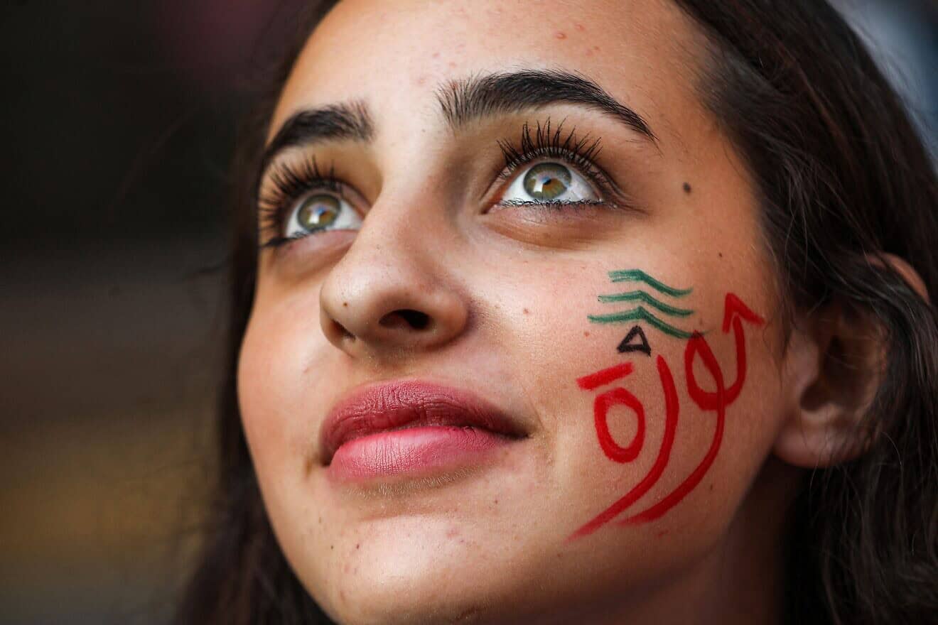 A woman wearing face paint depicting a Lebanese cedar tree and the Arabic word “revolution” looks on during a demonstration on the sixth day of protest against tax increases and official corruption in the center of the capital Beirut's downtown district on Oct. 22, 2019. Photo by Anwar Amro/AFP via Getty Images.