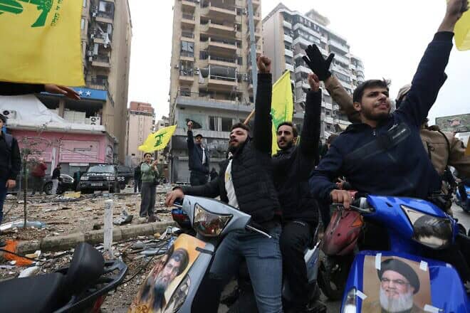 Hezbollah supporters wave the group's yellow flag during a parade on motorbikes while people returned to the area to check their homes in Beirut's southern suburbs on Nov. 27, 2024. Photo by Ibrahim Amro/AFP via Getty Images.