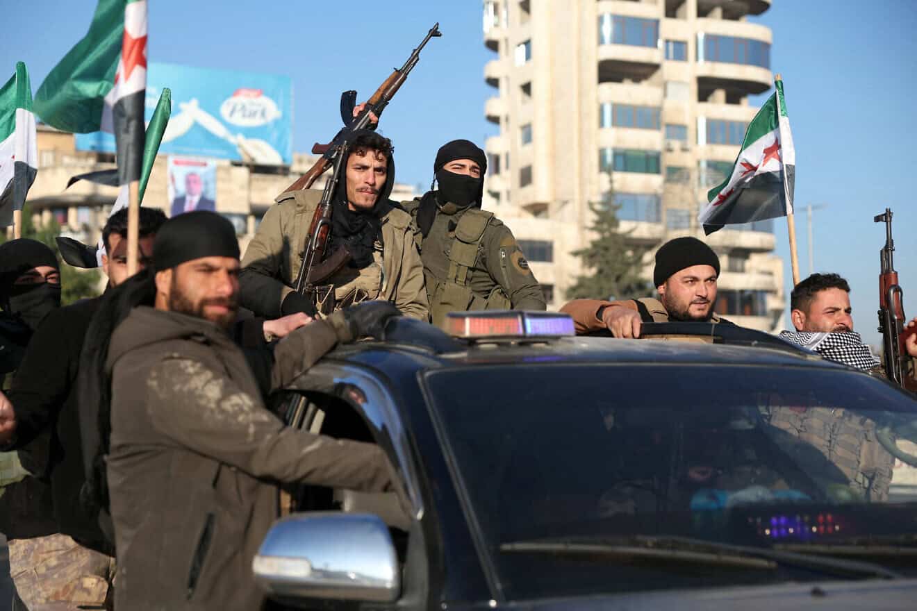 Anti-government fighters brandish their guns as they ride a vehicle in Syria's northern city of Aleppo on Nov. 30, 2024. Photo by Omar Haj Kadour/AFP via Getty Images.