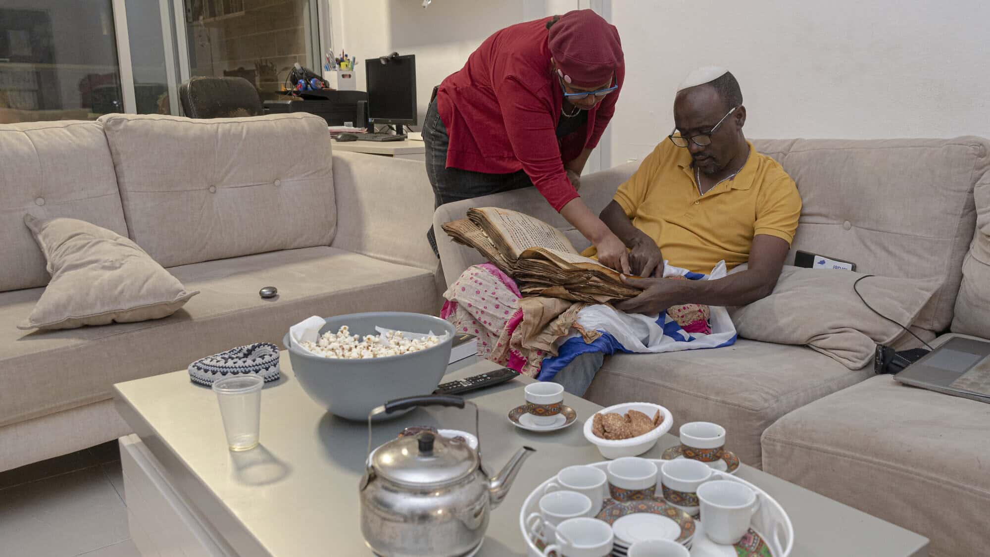Ayanawo Ferada Senebato and his wife, Mare, read a copy of the Orit, Ethiopian Jewry's version of the Hebrew Bible, at their home in Rishon Letzion, Israel, on Oct. 30, 2024. Photo by Canaan Lidor.
