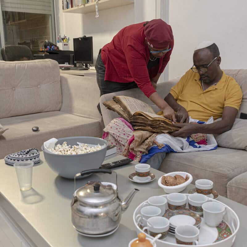 Ayanawo Ferada Senebato and his wife, Mare, read a copy of the Orit, Ethiopian Jewry's version of the Hebrew Bible, at their home in Rishon Letzion, Israel, on Oct. 30, 2024. Photo by Canaan Lidor.