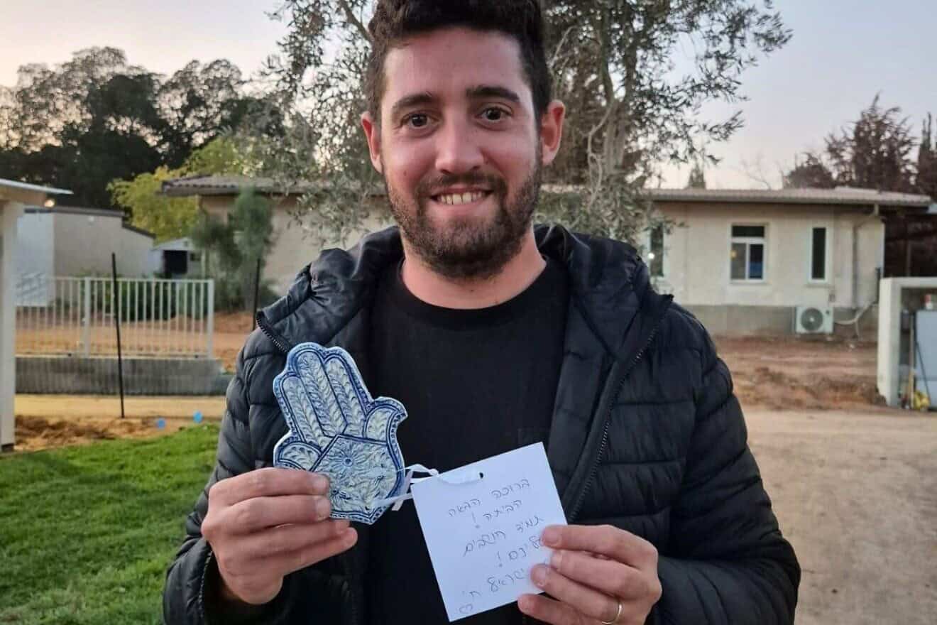 A resident of Kibbutz Kfar Aza in southern Israel displays a hamsa made specially for them by Australian Jews. Credit: KKL-JNF.
