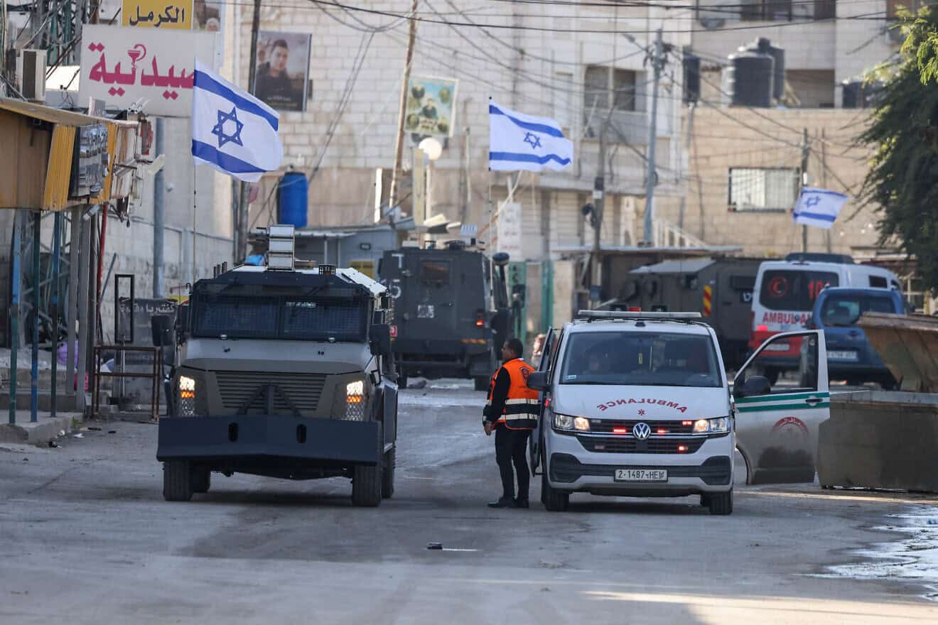An Israel Defense Forces military vehicle alongside a Palestinian ambulance in the Samaria city of Jenin, Jan. 21, 2025. Photo by Jaafar Ashtiyeh/AFP via Getty Images.
