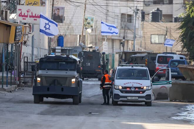 An Israel Defense Forces military vehicle alongside a Palestinian ambulance in the Samaria city of Jenin, Jan. 21, 2025. Photo by Jaafar Ashtiyeh/AFP via Getty Images.
