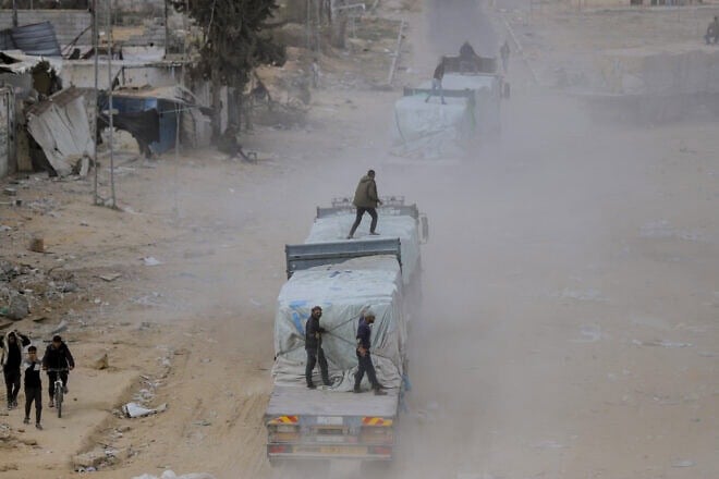 Palestinians secure aid trucks moving along a road after crossing into Gaza, following a ceasefire between Israel and Hamas, in Rafah in the southern Gaza Strip, Jan. 22, 2025. Photo by Saeed Jaras/Middle East Images/AFP via Getty Images.